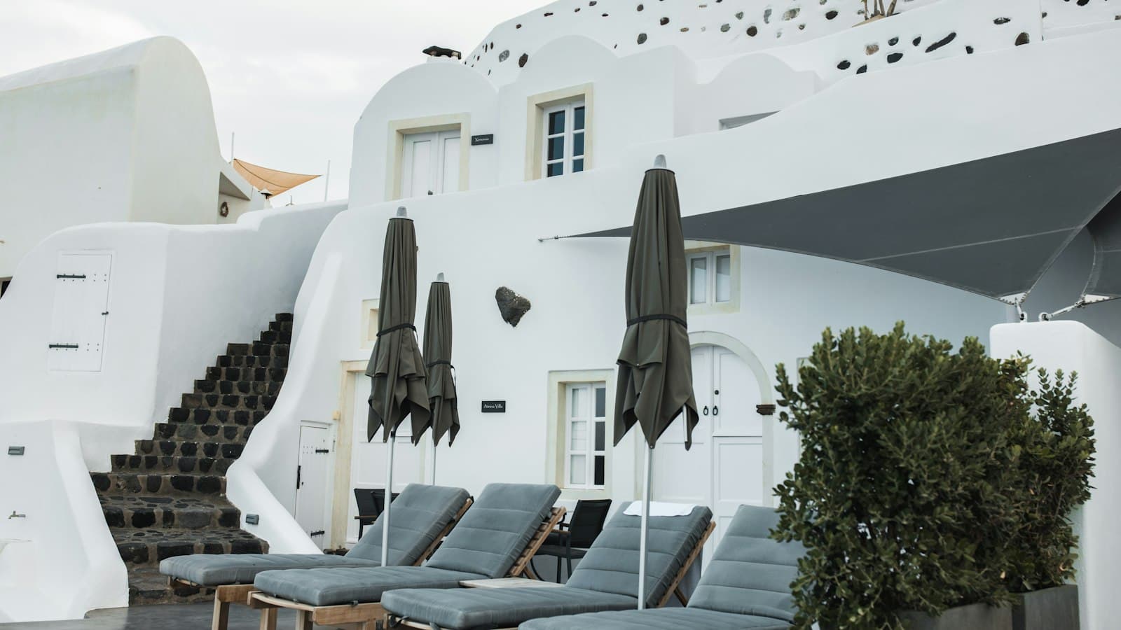 Whitewashed Santorini hotel terrace with sun loungers and closed parasols